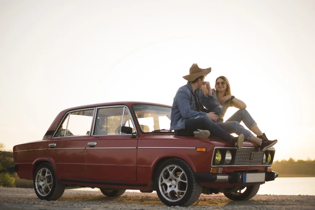 Pareja enamorada sobre un coche antiguo.