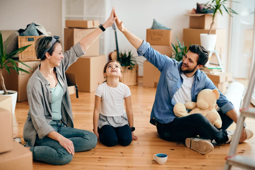 Pareja une sus manos para cubrir a su hija, simulando un hogar.