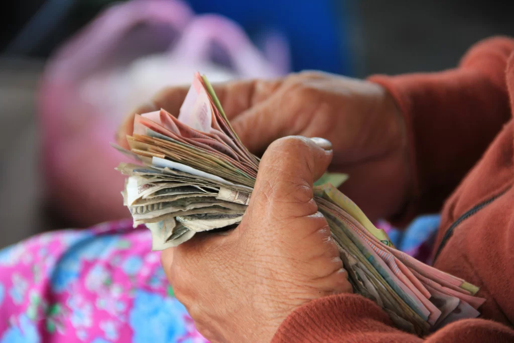 Faja de billetes envuelta por las manos de una mujer.