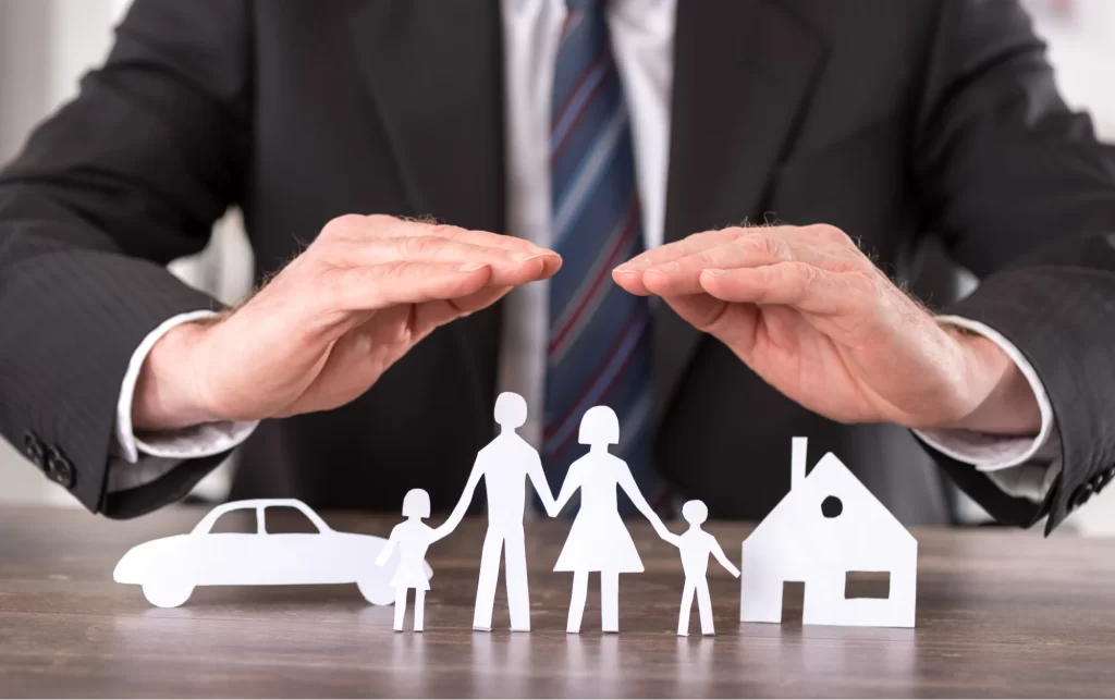 Manos cubren una casa con una familia.